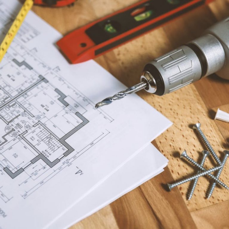 A drill on a piece of paper next to screws and a ruler