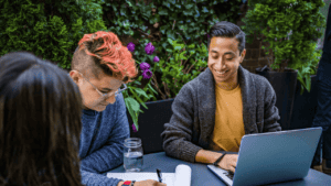 a group of people sitting at a table looking at a laptop
