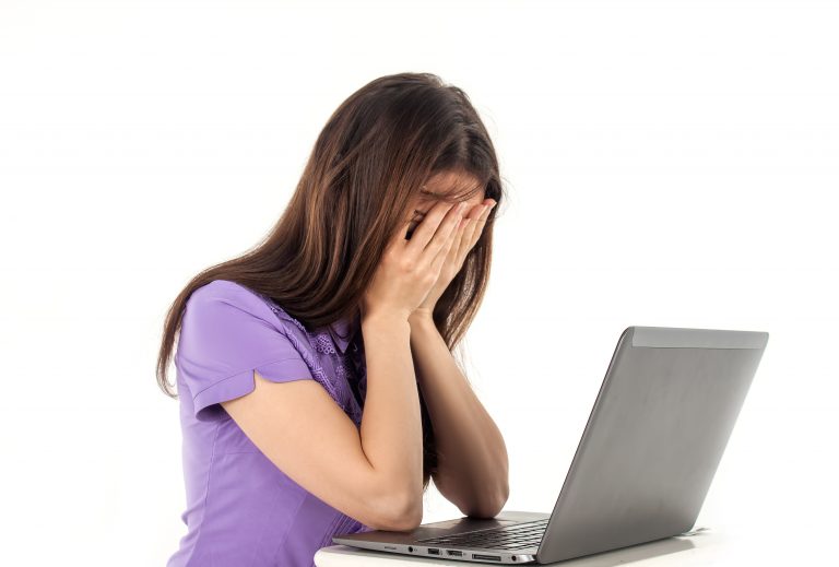 a woman with her hands on her face looking at a laptop