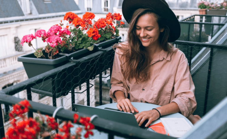 a woman sitting on a balcony with a laptop