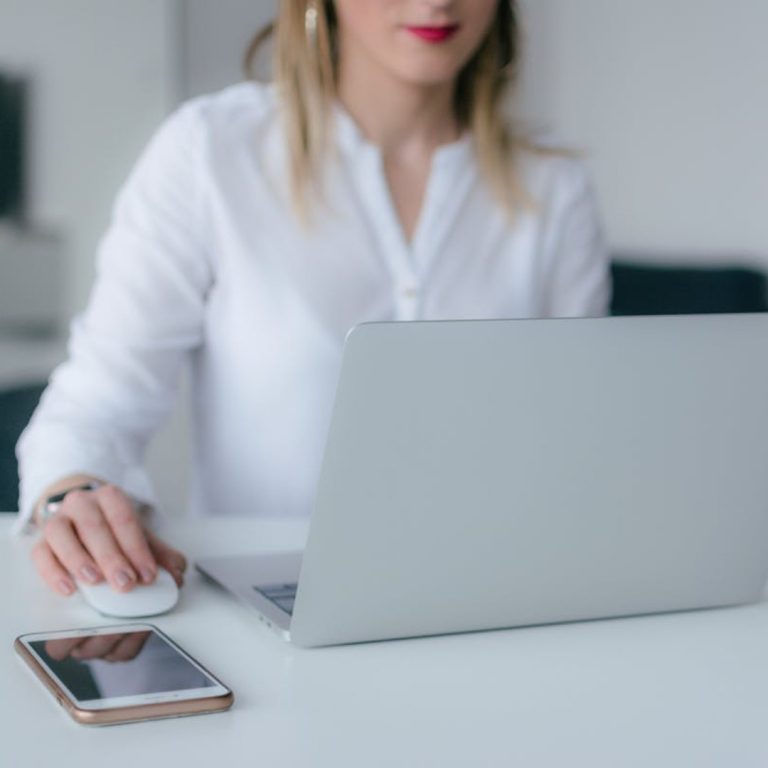 a woman sitting at a desk with a laptop and a phone