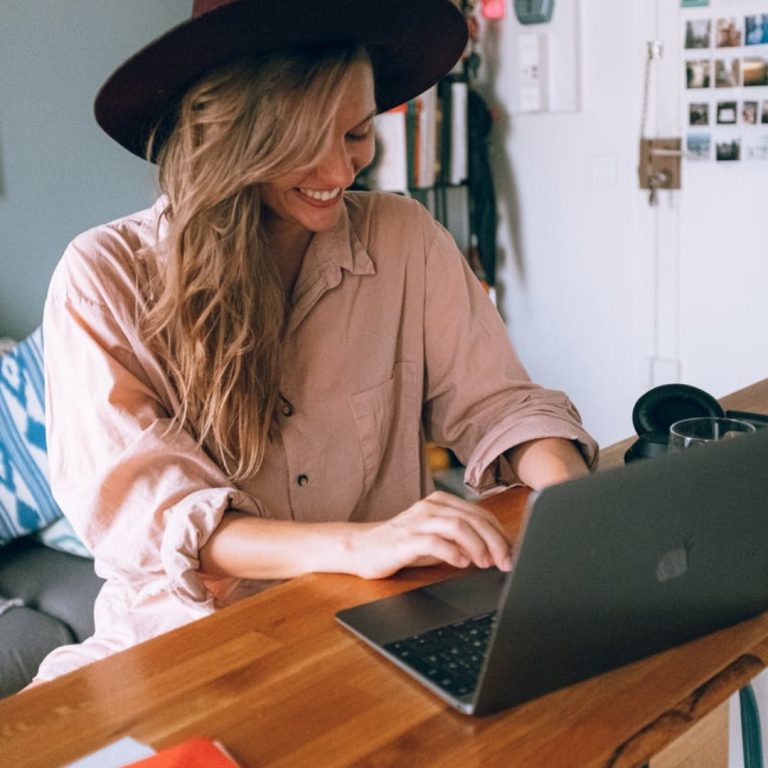 a woman in a hat using a laptop