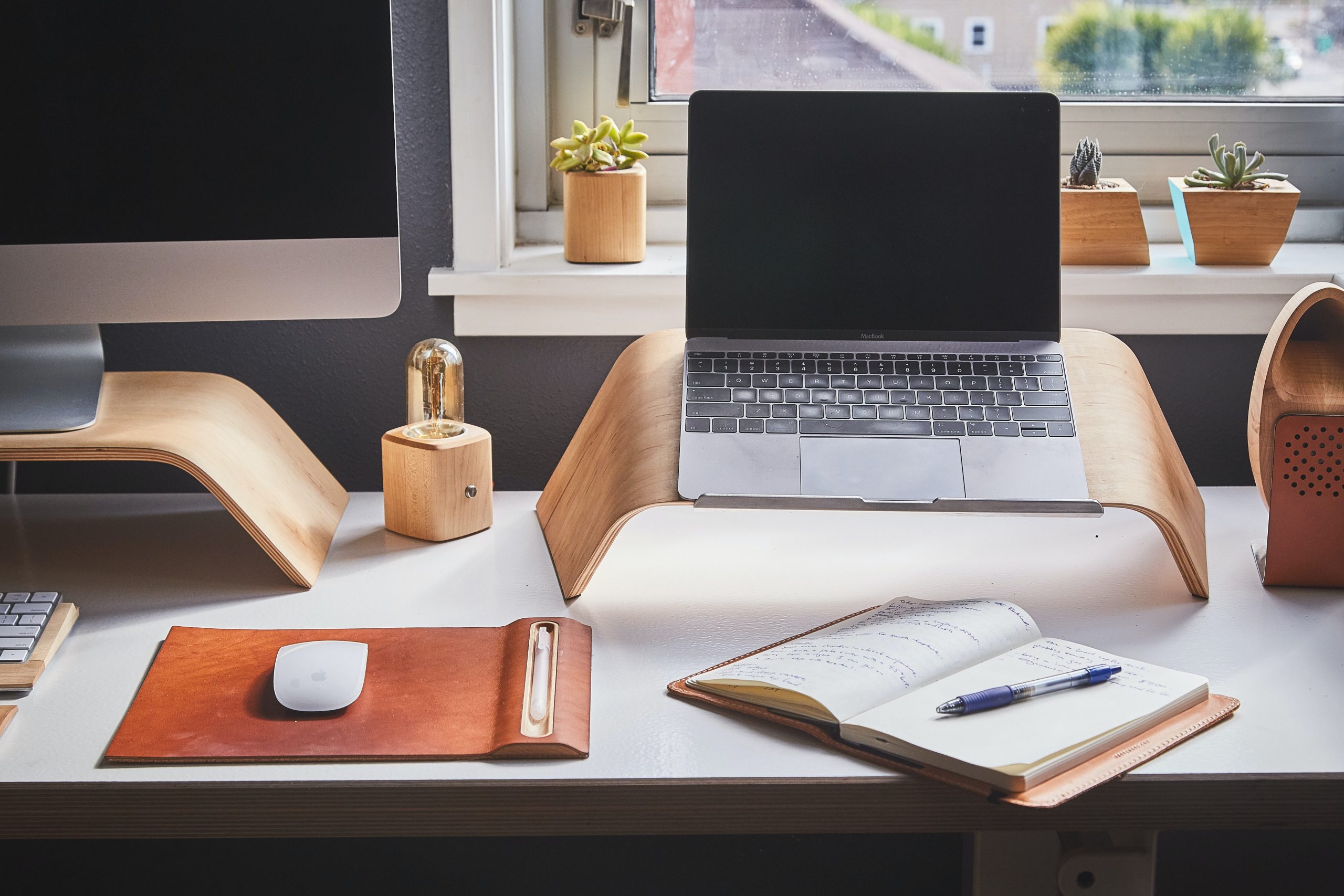 laptop computer and a PC on a table with a notepad and pen laptop computer and a PC on a table with a notepad and pen