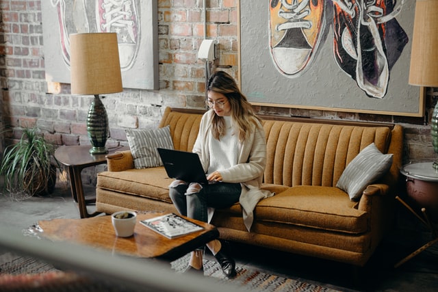 a woman sitting on a couch using a laptop