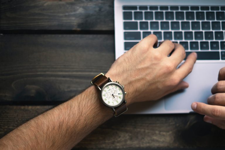 a person's wrist with a watch on a laptop