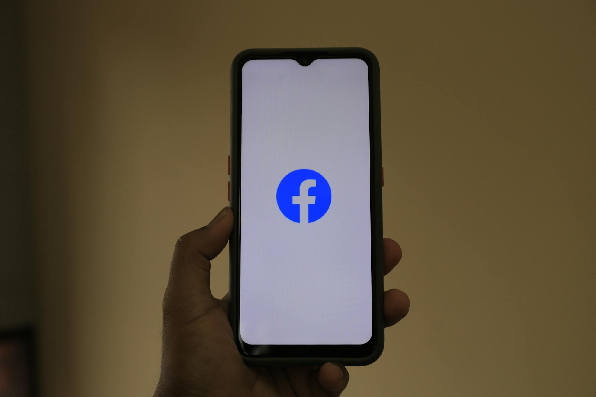Everest Series 1 A smartphone held in hand showing the Facebook logo on its screen.