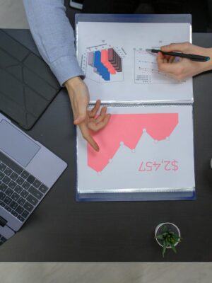 Business professionals discussing financial graphs at a desk with laptop and documents.